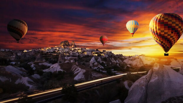 Colorful hot air balloon flying over rocky landscape at sunset