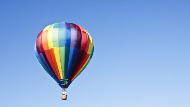 A colorful hot air balloon floating against a clear blue sky