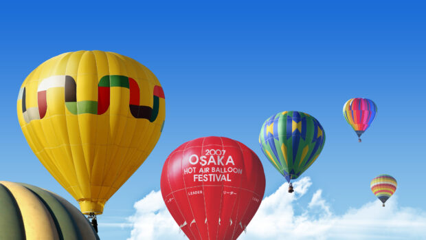 A colorful hot air balloon floating in the clear blue sky during a festival