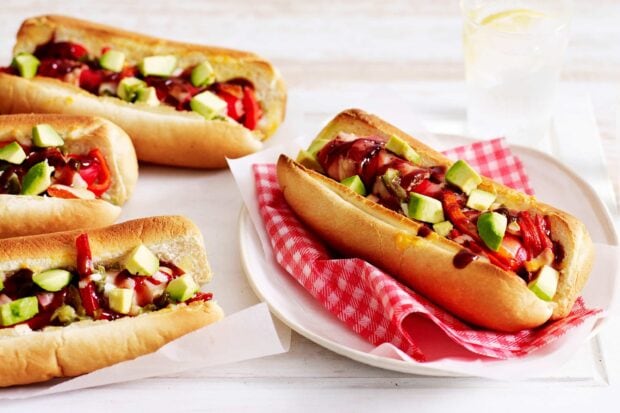 Delicious hot dog with fresh avocado and sauce on a toasted bun served on a plate