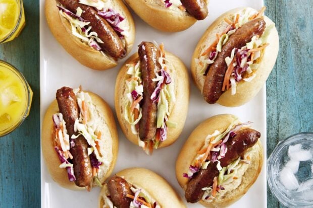 Grilled sausage served with shredded vegetables on fresh buns in a close up view