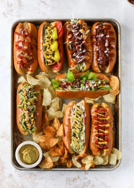 A variety of hot dog with different toppings served with potato chips on a tray