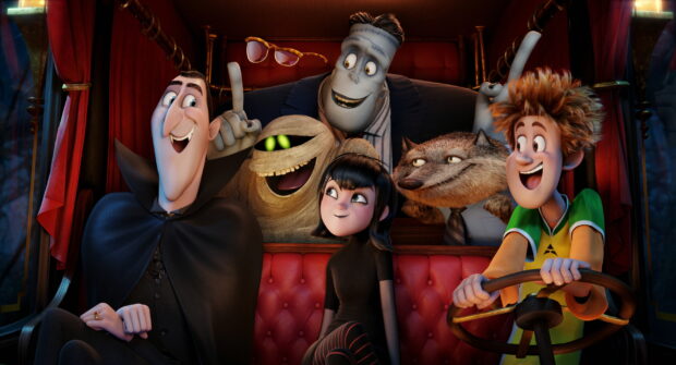 The main characters from Hotel Transylvania smiling inside a vintage car including a vampire mummy and werewolf