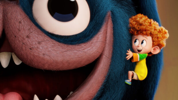A little boy with curly hair climbing on a large blue furry character from Hotel Transylvania