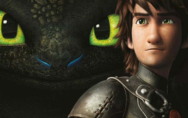 A close up of a How To Train Your Dragon character standing beside a dragon with green eyes