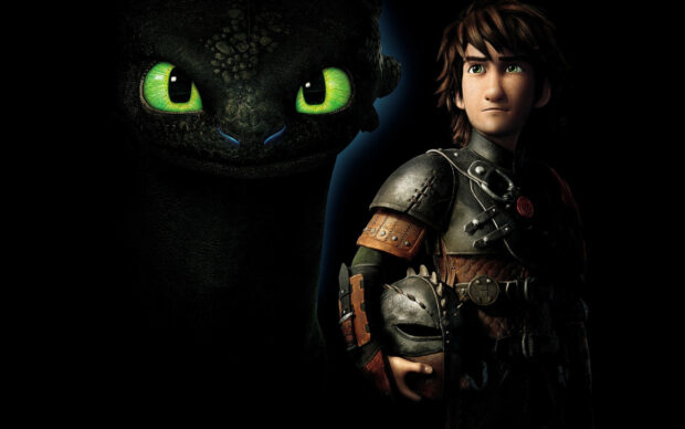 Hiccup holding a dragon helmet standing next to a dragon with bright green eyes from How To Train Your Dragon