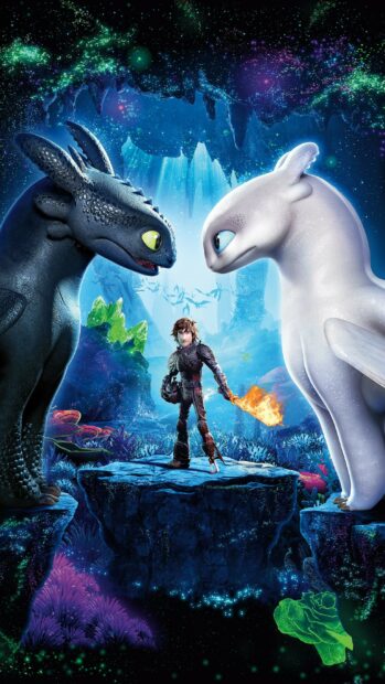 Hiccup stands between two dragons in a mystical cave setting from How To Train Your Dragon