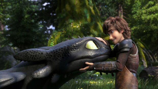 Hiccup gently touches the dragon's face in a forest setting from How To Train Your Dragon