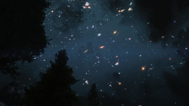 A view of the hubble deep field showing numerous distant galaxies against a dark sky surrounded by tree silhouettes