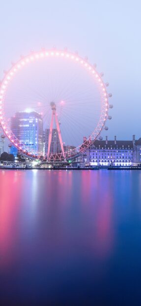 The London Eye shines brightly with pink lights against a blue sky over the river, 2K Phone Wallpaper
