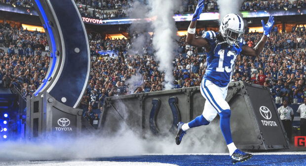 A Indianapolis Colts player wearing number 13 running onto the field through smoke during a game opening ceremony