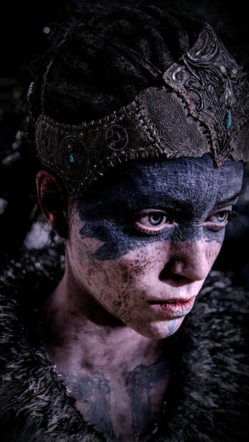 A close up of an intense warrior with face paint and detailed headgear in Hellblade HD Mobile Wallpaper