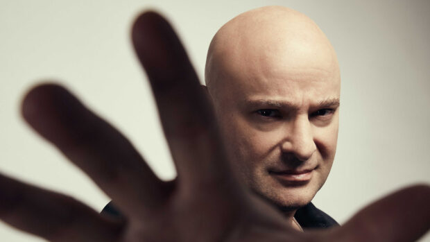 A bald man shows an intense facial expression with an outstretched hand, 2K Desktop Wallpaper