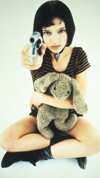 A determined girl holding a gun while clutching a stuffed bunny in this Leon Wallpapers scene, HD Mobile Wallpaper