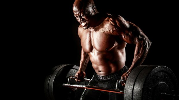 A muscular man demonstrates intense powerlifting strength with heavy weights, 2K Desktop Wallpaper
