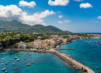 A scenic view of Ischia island with numerous boats and vibrant coastal town under a blue sky