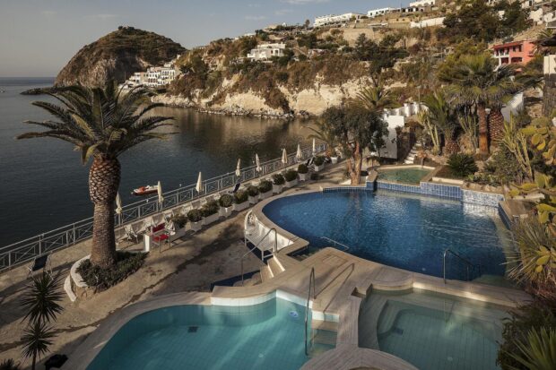 Scenic coastal view with palm trees and a luxury pool in Ischia island