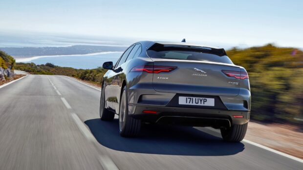 A Jaguar I Pace is driving along a scenic coastal road with clear skies, HD Desktop Wallpaper