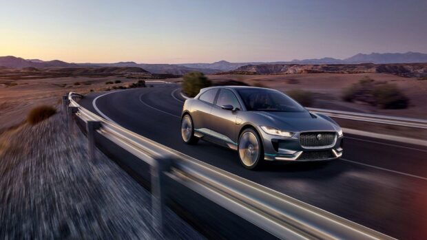 A Jaguar I Pace is seen driving fast on a winding road in a desert landscape, HD Desktop Wallpaper