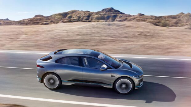 A Jaguar I Pace is driving fast along a desert highway with mountains in the background, 4K Desktop Wallpaper