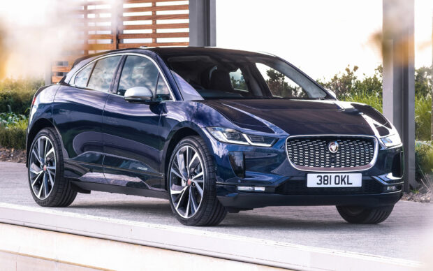 A dark blue Jaguar I Pace electric SUV is parked outdoors near a modern structure, HD Desktop Wallpaper