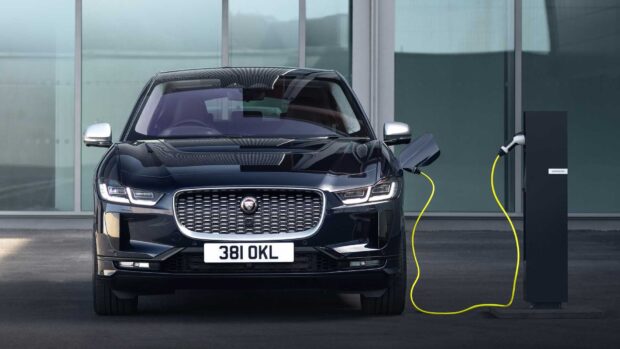 A Jaguar I Pace is connected to a charging station in front of a modern building, HD Desktop Wallpaper