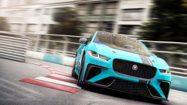 A blue Jaguar I Pace car is racing on a city street corner with blurred background, 4K Desktop Wallpaper
