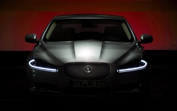 Front view of a Jaguar car showcasing the Jaguar logo on the grille in a dark setting