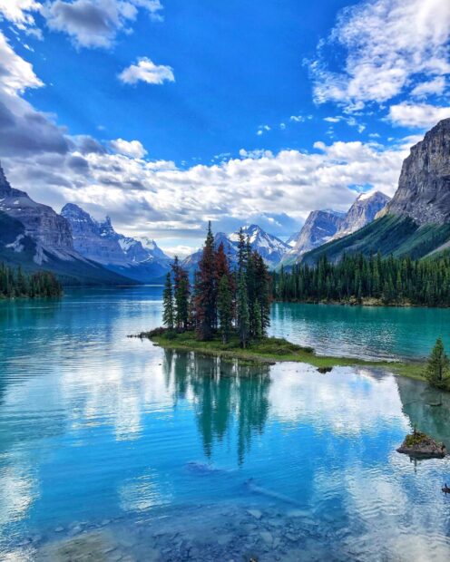 Small island with pine trees in a lake surrounded by mountains in Jasper National Park