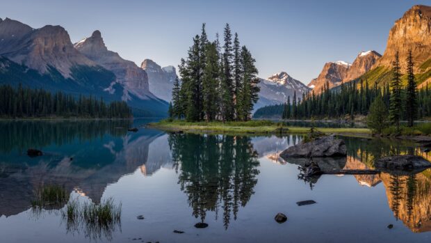 A serene lake with pine trees and mountains in Jasper National Park reflecting in clear water