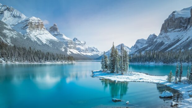 Snowy mountain peaks and pine forest surround Jasper National Park lake in winter