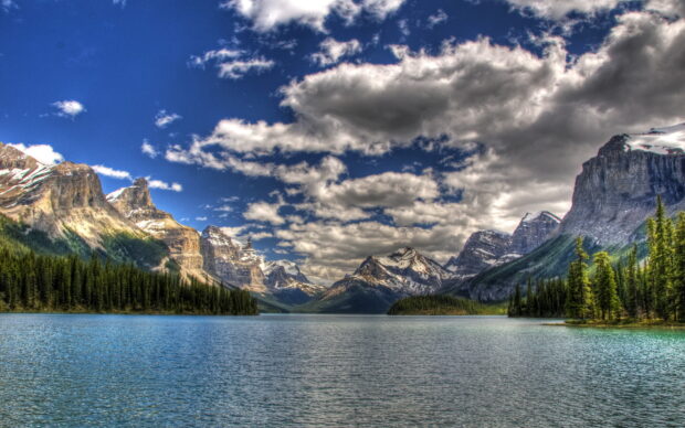 Mountain range and forest landscape in Jasper National Park with clear blue lake and cloudy sky