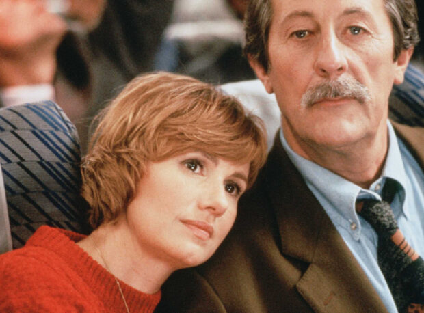 A woman resting her head on a man's shoulder in a scene featuring Jean Rochefort, 2K Desktop Wallpaper