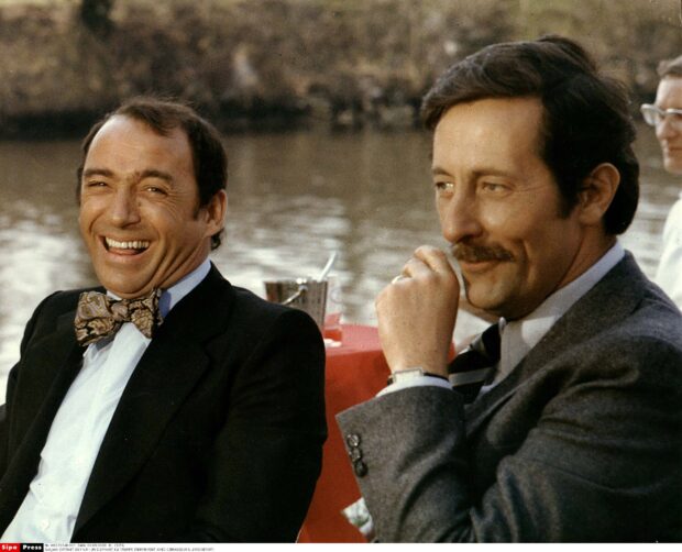 Jean Rochefort is smiling and sitting beside a man by the river, HD Desktop Wallpaper