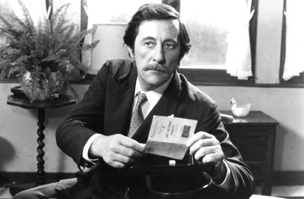 Jean Rochefort is sitting and holding a paper in a classic black and white scene, 2K Desktop Wallpaper
