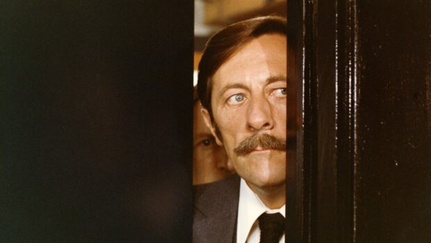 Jean Rochefort looking thoughtfully through a partially open door with a serious expression, 4K Desktop Wallpaper