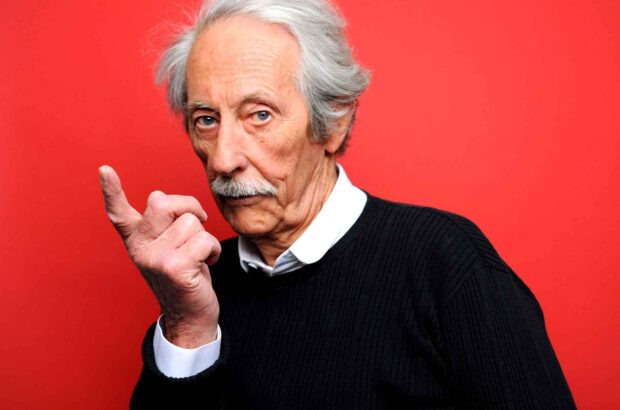 Jean Rochefort appears wearing a black sweater against a red background, HD Desktop Wallpaper