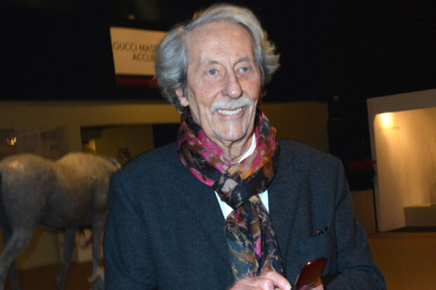 Jean Rochefort is smiling warmly while wearing a colorful scarf and dark jacket indoors, 2K Desktop Wallpaper