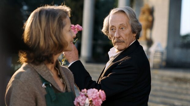 Jean Rochefort touching a woman's face while she holds pink flowers outdoors, 4K Desktop Wallpaper