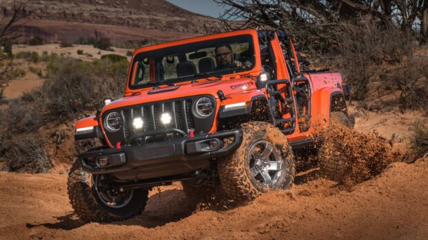 Jeep Gladiator driving through muddy terrain in a desert setting with dirt flying