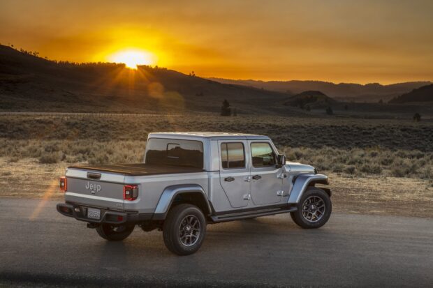 Jeep Gladiator parked on a road during sunset in an open landscape with hills and dry grass