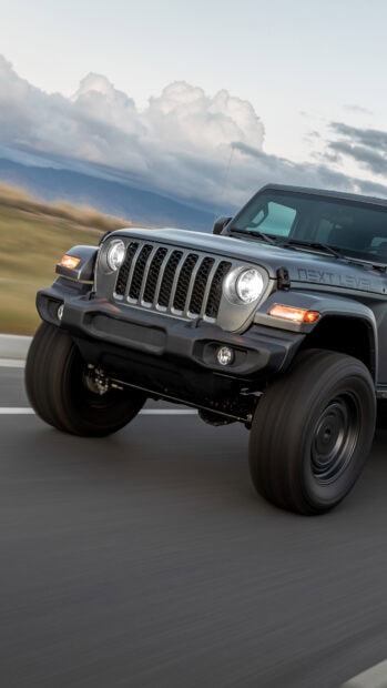 Jeep Gladiator driving fast on the road under a cloudy sky