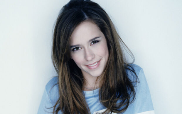 Jennifer Love Hewitt smiles softly wearing a blue shirt against a plain background, HD Desktop Wallpaper