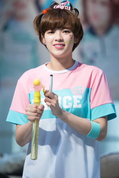 Jeongyeon Twice wallpapers shows a smiling woman holding a yellow toy in a colorful outfit, HD Mobile Wallpaper
