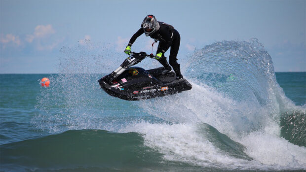 A rider performs a jump on a jet ski creating a splash over the ocean, HD Desktop Wallpaper