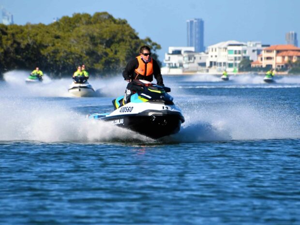 A person riding a jet ski speeds across the water with others in the background during a sunny day, HD Desktop Wallpaper
