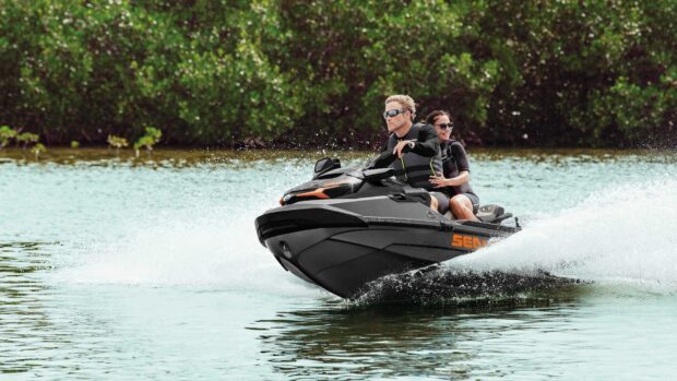 A couple enjoys jet ski riding on calm water with lush greenery in the background, HD Desktop Wallpaper
