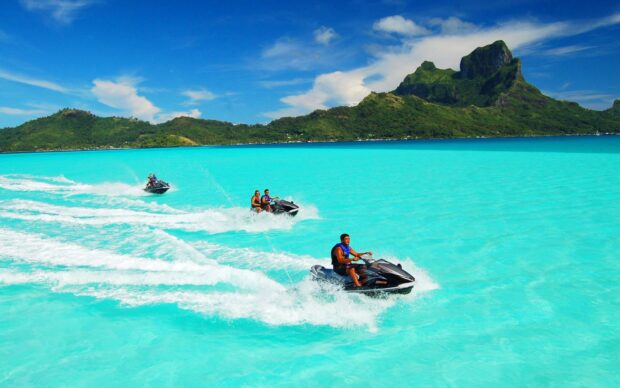 People riding jet skis on turquoise water near green island, HD Desktop Wallpaper