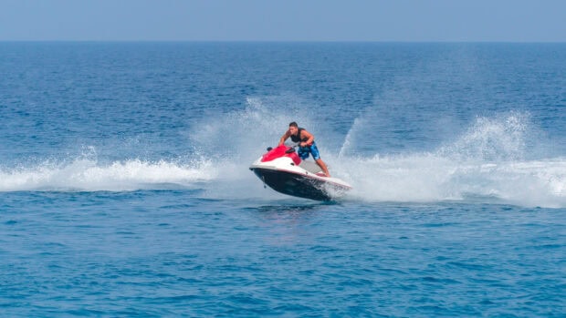 A man is riding a jet ski creating water splashes on the calm blue sea, HD Desktop Wallpaper