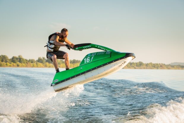 A man riding a green jet ski jumping high above the lake water, HD Desktop Wallpaper
